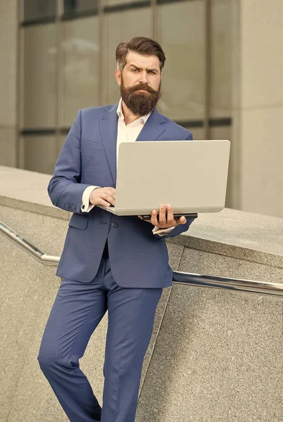 Фрилансер в формальном костюме работает в режиме онлайн с помощью ноутбука компьютерного устройства современной технологии на открытом воздухе, фрилансер — стоковое фото