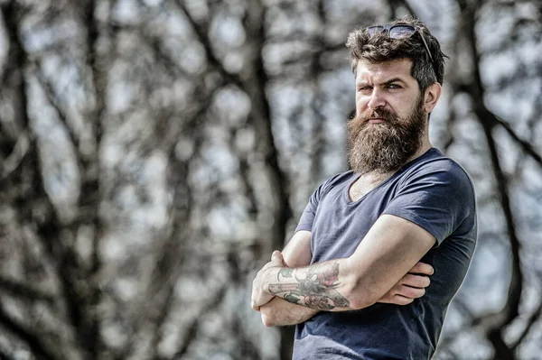 Masculinity and manliness. Man attractive bearded hipster posing outdoors. Confident posture of handsome man. Guy masculine appearance with long beard. Barber concept. Beard grooming. Beard care