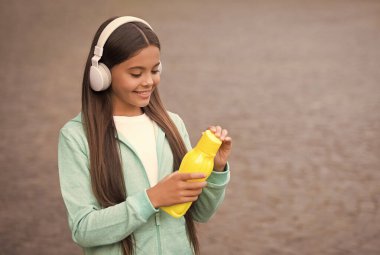 Aktif ve sağlıklı çocuklar su içer. Kulaklığında meyve suyu şişesi olan bir çocuk. Okula dönüyorum. Çocuklukta sağlık hizmetleri. Gençler için sağlıklı bir içki. Formdan sonra susadım. Kız bakım vücut sıvısı.