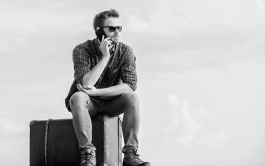 Bir bilet ayırt. Gezgin, taksi bekle. Çekil şuradan. Seksi adam gökyüzü arka planı telefonda konuşuyor. Maço turist rahat tur çantası. Erkek modası. Çok modaya uygun görünüyorsun. Gözlüklü iş adamı. iş gezisi