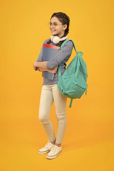 Nowoczesna uczennica z plecakiem i zaopatrzeniem szkolnym żółte tło, koncepcja dzień wiedzy — Zdjęcie stockowe