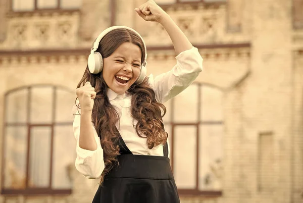 Mi día perfecto. felicidad infantil. niño en auriculares digitales. pequeña estudiante escuchar música al aire libre. de vuelta a la escuela. niña pequeña que parece inteligente e inteligente. colegiala feliz en uniforme elegante — Foto de Stock