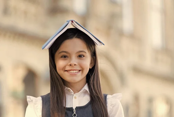 Bekam das Buch, das sie braucht. Glückliches Kind hält Buch auf dem Kopf im Freien. Kleiner Bücherwurm mit langem Haar. Schulbibliothek. Formale Bildung. Wissen und Information. Kreativität und Fantasie — Stockfoto