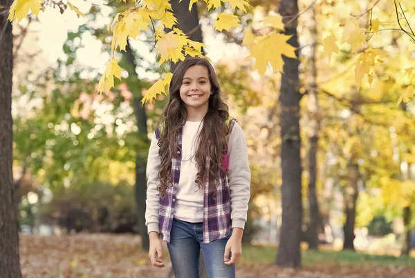 Chica feliz en estilo casual pasar tiempo caminando en el parque de otoño disfrutando del buen tiempo llevar mochila, de vuelta a la escuela — Foto de Stock