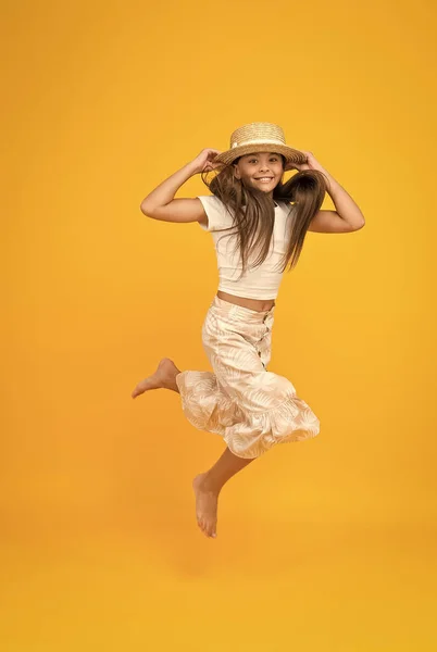 Sensación de libertad. felicidad infantil sin preocupaciones. niña pequeña usar traje de verano. moda de vacaciones de verano. Feliz día de los niños. divertirse en la fiesta de playa. Niño con sombrero de paja. feliz salto de niño descalzo —  Fotos de Stock