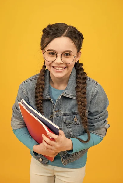 Niño feliz con mirada nerd celebrar libros de la escuela en el estilo casual de la moda de fondo amarillo, de vuelta a la escuela — Foto de Stock