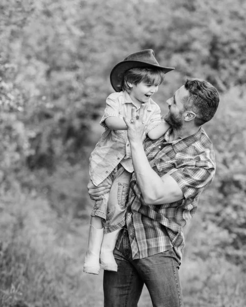 Эко-ферма. Маленький мальчик помогает отцу в сельском хозяйстве. Отец и сын в ковбойской шляпе на ранчо. ребенок в резиновых сапогах. счастливый отец в лесу. человека и природу. День семьи. Счастливого Дня Земли. счастливая семья — стоковое фото