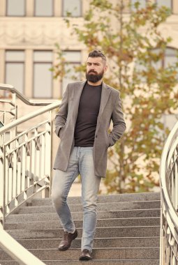 Sakallı hippi, şık saçlı. Ceket ve kot pantolon giyiyor. Yürüyüş, güzellik ve moda için.