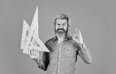 Evde ders çalış. Eğitim. Okul öğretmeni üçgen kullanır. Matematik ve geometri dersi. Okula dönüyorum. Mühendisliğe hazır. Grafikler için araç. Olgun sakallı adam, üçgen cetvel tut