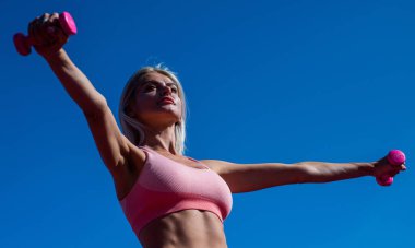 Spor giyim sektöründe sportif bir kadın. Stadyum spor salonundaki seksi kadın. Kadın antrenör. Koç halterleri kullanın. Spor başarısı. Dambıl. Fitness sporu modası. Bayan ağırlık kaldırıyor.