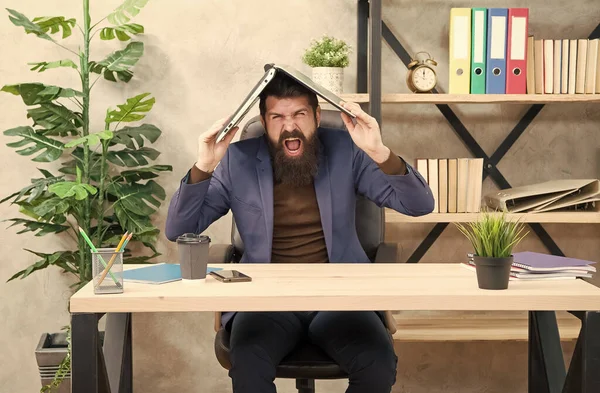 Hullu liikemies liikepuvussa huutaa äänekkäästi pitämällä muistikirjaa päänsä päällä modernissa toimistossa, epätoivo — kuvapankkivalokuva