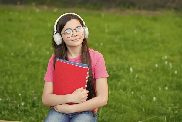 Звук, щоб зруйнувати ваше життя. Маленька дитина слухає музику на зеленій траві. Маленька дівчинка носить аудіо навушники. Прослуховування аудіо- подкасту. Нова технологія. Сучасне життя. Звук Hi-Fi. Відтворення настрою в аудіо — стокове фото