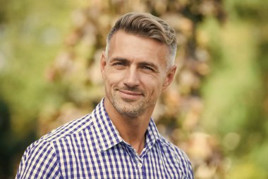 Pozitif insan duygularını ifade et. Olgun traşsız erkek gömleği. Erkek güz mevsimi modası. Dışarıda gülümseyen yakışıklı adam. Erkek saçı güzellik ve bakım. Berber salonu. yüz bakımı konsepti