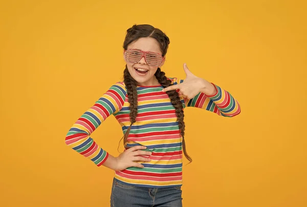 Gelukkig tiener meisje met gevlochten haar dragen casual stijl regenboog kleur en glamour partij bril op gele achtergrond, positieve — Stockfoto