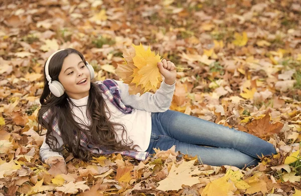Tökéletes hely a szállásra. gyermek pihenni őszi erdőben. őszi juharfalevelek a parkban. Gyerekkori boldogság. szépség és természet. Happy gyerek fejhallgatót visel. tini lány zenét hallgatni az iskolába menet — Stock Fotó