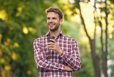 Burada olmak güzel. Yakışıklı adam kareli gömlek giyiyor ve elinde çay fincanı tutuyor. Adam dışarı çıkmak için kahve içiyor. İnsanoğlu kendini yeniler. Tıraşsız mutlu öğrenci sabah kahvesi içer. Günaydın ilham.