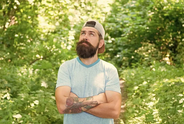 Lejos de la ciudad. hombre hipster senderismo. cuidado de la barba masculina. brutal hipster en el bosque. descubrir nuevos lugares. Hora del picnic. Un tipo soñando despierto con bigote. hombre barbudo maduro con gorra. vacaciones de campamento de verano — Foto de Stock