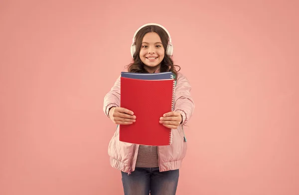 Verslaafd aan boeken. Gelukkig kind houden boeken roze achtergrond. Kleine boekenworm draagt een koptelefoon. Luisteren naar audio boeken. Muzikale notatie. Taalcursussen Engels. Schoolbibliotheek. Literatuur van kinderen — Stockfoto