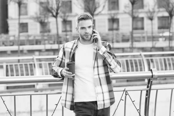 Lets meet in few minutes. Modern life communication. Modern guy with smartphone urban background. Handsome man mobile phone and coffee cup. Modern technology. Conversation with friend. Call me later