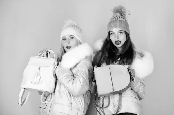 Fashion friends. Winter clothes. Women wear down jacket with furry hood.  Girls smiling makeup faces wear winter jackets blue background. Winter  season. Soft fur. For those wishing stay modern - Stock Image 