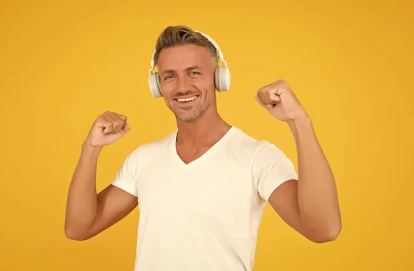 La música es poder. Feliz hombre brazos flexibles fondo amarillo. Potencia de audio. Escuchando música. Tecnología de auriculares. Estilo de vida moderno —  Fotos de Stock