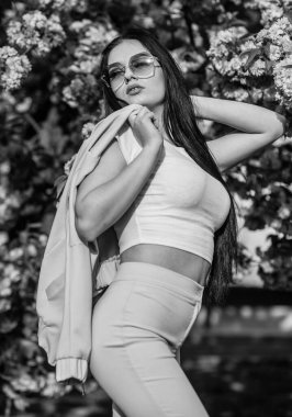 Çiçekli bahar bahçesinde muhteşem bir kız. Doğanın yeşillikleri ve çiçekleri. Mutlu Paskalyalar. Seksi kız sakura çiçeğinin tadını çıkarıyor. Kiraz çiçekli kadın. Ağaç dalı ve büyüleyici bayan. Çekici esmer kız.