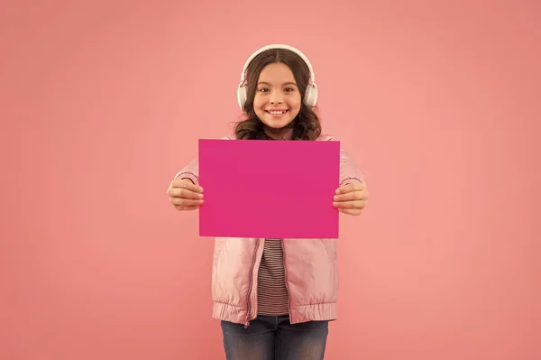 Bambino allegro con gli auricolari e mostrando carta vuota per lo spazio copia, annuncio — Foto Stock