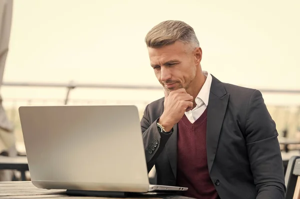 Handsome business man in formal style use computer technology for working online outdoors, e-business