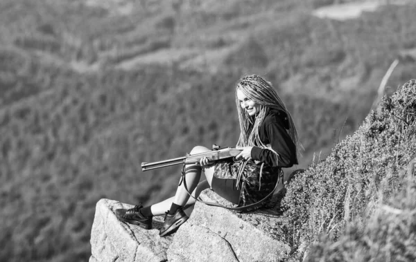 Aiming concept. Amazon girl sit on cliff prepare gun for hunting. Hunting season. Hunter mountains landscape background. Sexy warrior. Woman attractive long hair pretty face hold rifle for hunting — Stock Photo, Image