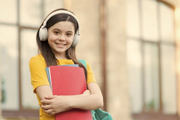Menina moderna com fones de ouvido de volta à escola segurar livro didático, aprendendo cada conceito minuto — Fotografia de Stock