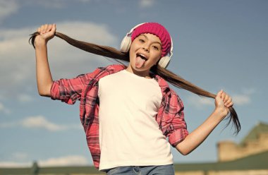 Komik kız müzik dinlerken dili dışarı çıkıyor ve uzun esmer saçlar tutuyor güneşli gökyüzü, saç bakımı