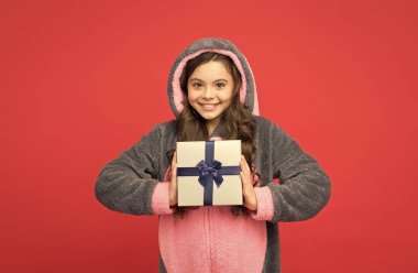 Mutlu çocuk hayvan pijaması giyer ve hediye kutusunu tutar. Mutlu yıllar.