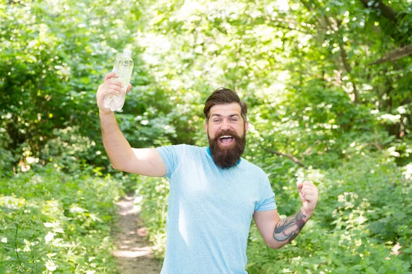 Glad skäggig man håller flaskan. mogen hipster med skägg i skogen. sommarvärme — Stockfoto