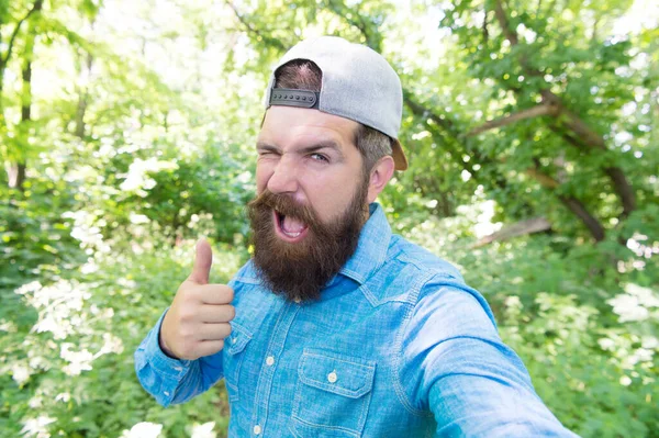 幸せな成熟した髭を生やした男が夏の森の中で自撮り写真を作る親指を表示します,喜び — ストック写真
