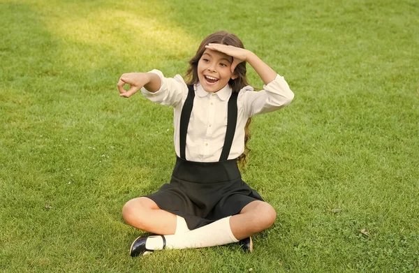Criança feliz em uniforme escolar olhar em frente apontando dedo verde grama paisagem natural ao ar livre, futuro — Fotografia de Stock