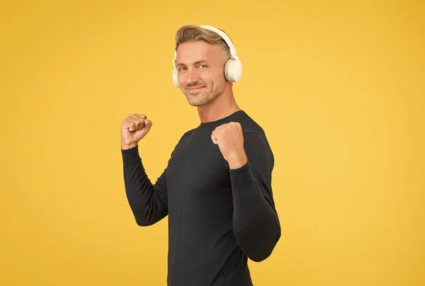 Handsome happy male with nice smile demonstrate high quality headset being in good mood while listening music online, techno shop — Stock Photo, Image