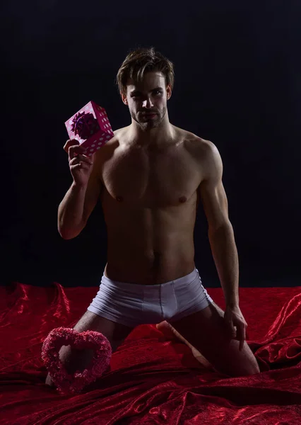 Musculoso y atlético. salud sexual y libido. deseo y juegos eróticos. hombre desnudo sostiene caja de regalo. relaciones sensuales y sexy. hombre con el pecho desnudo en pantalones. regalo de San Valentín — Foto de Stock