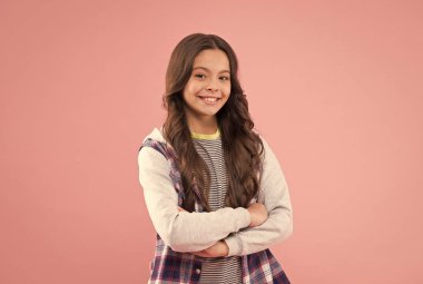 Kendine güven ona çok yakıştı. Kendine güvenen çocuk kollarını pembe arka planda tutuyor. Moda kızının kendine güveni tam. Sıradan moda trendi. Modayı takip eden çocuklar giyer. Çocuk kıyafetleri. Kendine güvenen güzellik