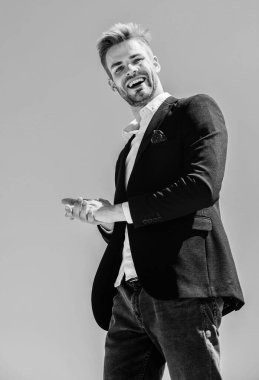 Mavi gökyüzü arka planında resmi takım elbiseli yakışıklı bir adam. Ofis çalışanı. Çalışmaya hazırım. Erkek modası. Resmi tarz. Kendine güvenen yakışıklı iş adamı. Yakışıklı bir manken. Kusursuz görünüyor.