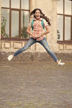 Mutlu enerjik çocuk okul bahçesinde kulaklıkla müzik çalıyor, mutluluk.