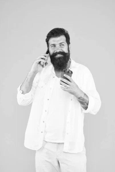 Ragazzo allegro con i baffi e la barba bere caffè e parlare su smartphone, comunicazione — Foto Stock