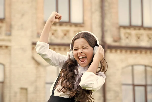 Una pupila sonriente. Un verdadero éxito. Feliz canción. Ocio y descanso. Hermoso peinado. Niño feliz al aire libre. Una colegiala alegre. Colegiala relajándose. Concepto de infancia feliz. Día internacional de los niños — Foto de Stock