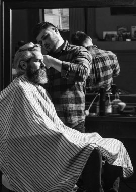 Yüze yakın keskin bir nesne ve kıvranma onu tutan kişinin dikkatini dağıtır. Saç bağışı. Bağış ve yardım konsepti. Sarıya boyanmış saçlı adam. Saç kes. Berber berber dükkanı. Hippi saçını kestiriyor.