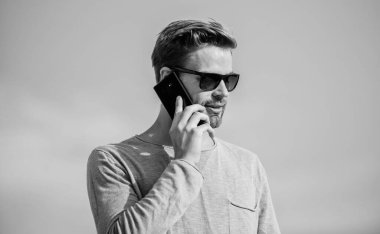 Çevik iş. Seksi erkek gökyüzü arka planı. Hayattaki modern teknoloji. Her zaman görüşüyoruz. Kendine güvenen bir adam telefonda konuşur. Arkadaşına seslen. Maço adam cep telefonu kullanıyor. Sıradan bir adam. Moda modeli