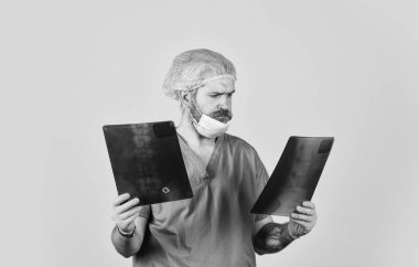 Hastane acil durumu. Cerrah zararları tahmin ediyor. Doktor üniforması. Röntgen konsepti. X ışını radyasyonu. Doktor kemiklerin resimlerini tutuyor. Kırık ve kemik hasarı. Doktor radyografik görüntüyü inceliyor.