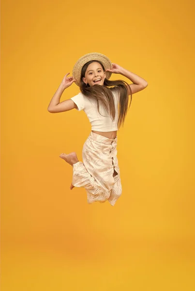 Niño súper activo saltar en sombrero de paja. niño descalzo sentir la libertad. Lleno de felicidad. moda de verano para niños. niña saltando alto sobre fondo amarillo. niño enérgico de vacaciones —  Fotos de Stock