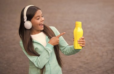 Mutlu genç kız parmağını su şişesini işaret ederek içecek ve içecek.