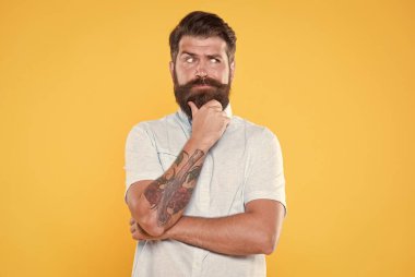 Beyaz gömlekli, sakallı, düşünceli bir adam.