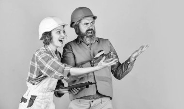 Mükemmel görünüyor. Kadın ve erkek emniyet başlığı takıyor. Aile evin içinde inşaat halinde. Yenileme ve insan konsepti. İnşaatçı çift ev planlarına bakar. Bir plana bakan çift.