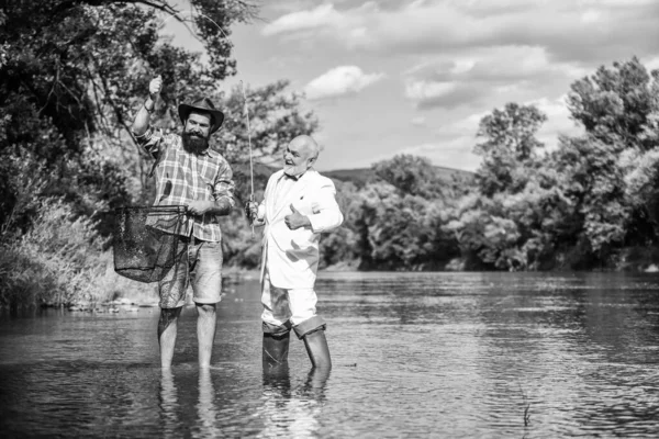 Weekend con la famiglia. Buona amicizia tra pescatori. hobby del pesce della mosca dell'uomo d'affari. pesca a riposo. Due amici maschi che pescano insieme. Concetto di cattura e pesca. pensionato papà e maturo figlio barbuto — Foto Stock